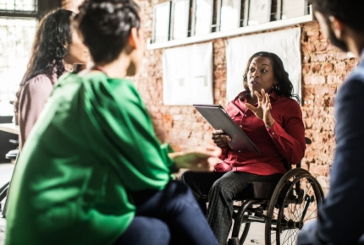 Businesswoman in wheelchair leading group discussion in creative office