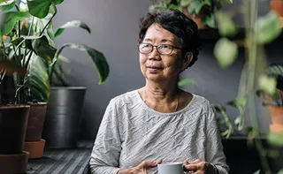 Mature person drinking tea on their balcony