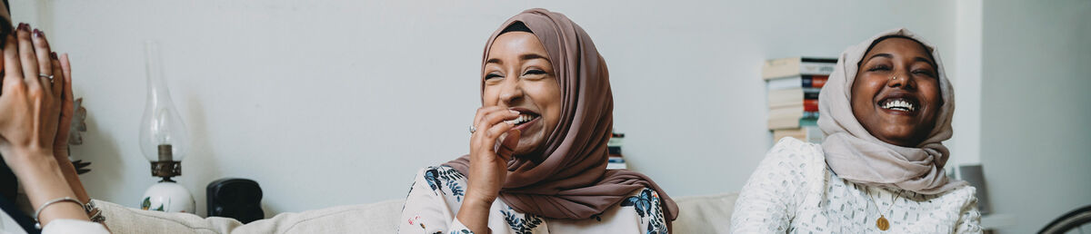 Close up of person in brown scarf, talking with a group of colleagues