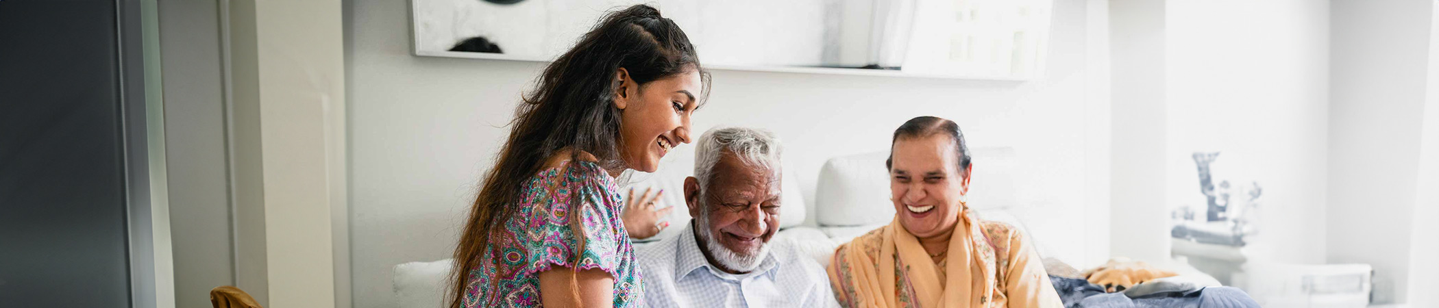Young person smiling showing smiling older couple their mobile phone