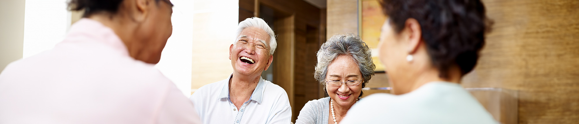 Four older people seated around a coffee table and smiling