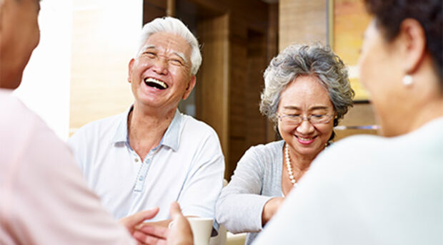 Four older people seated around a coffee table and smiling