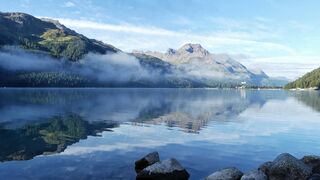 A body of water surrounded by mountains and forest