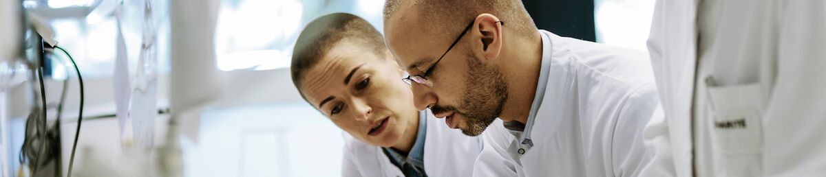 Three scientists leaning over a lab desk looking at something together