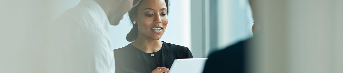 Two smiling colleagues standing together looking at an iPad