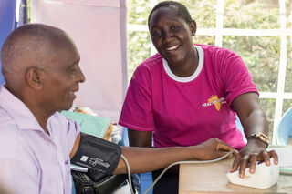 A community volunteer taking a person’s blood pressure reading